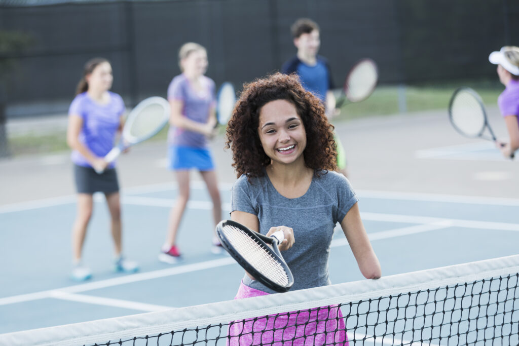 Physically challenged teenage girl (amputee) taking tennis clinic. 