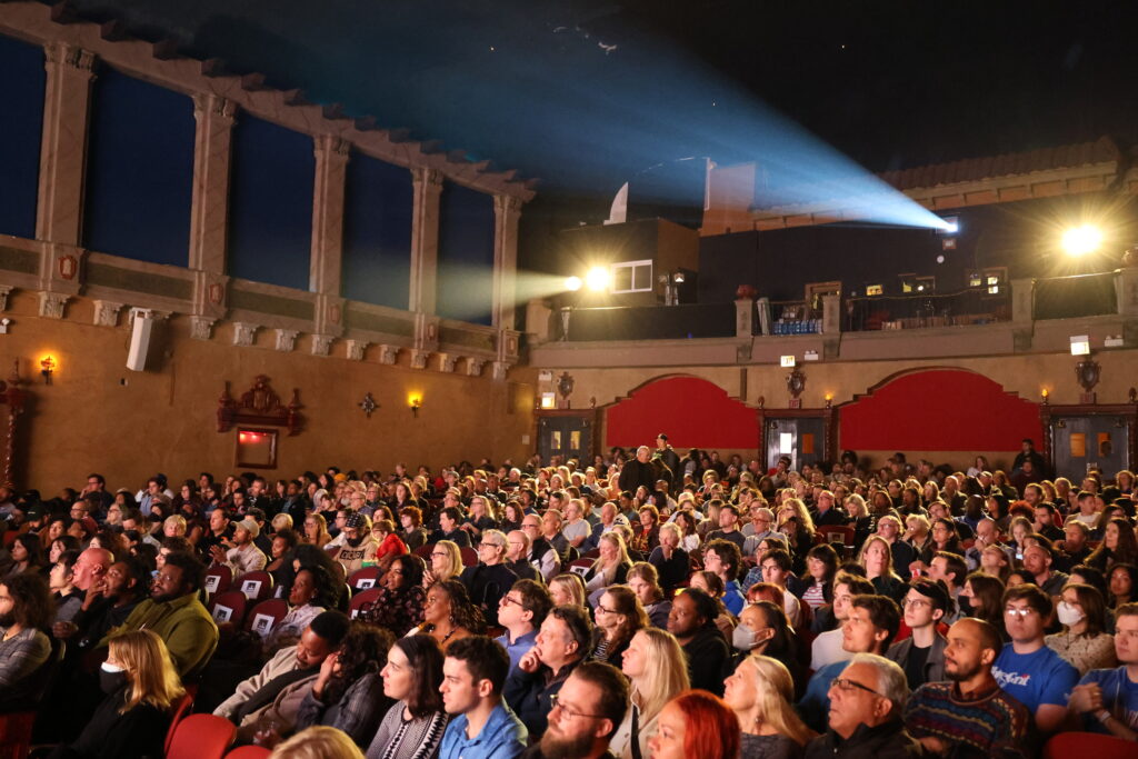 A color image of moviegoers in a theater watching a film