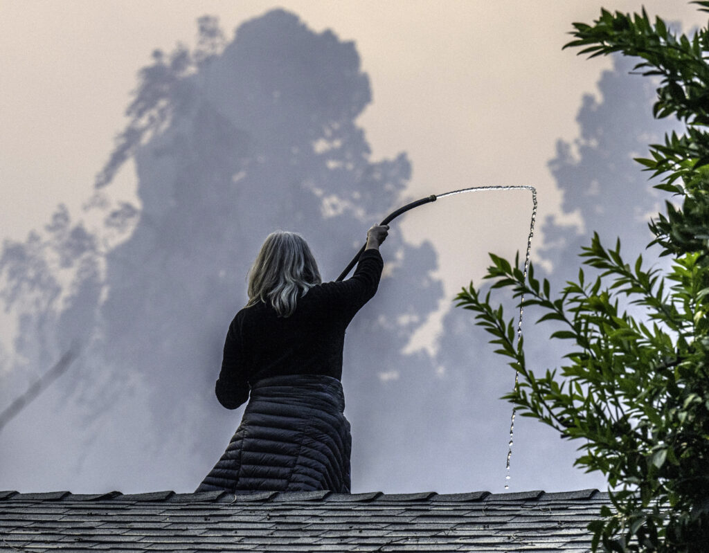 A homeowner attempts to protect her property from the Palisades fire.