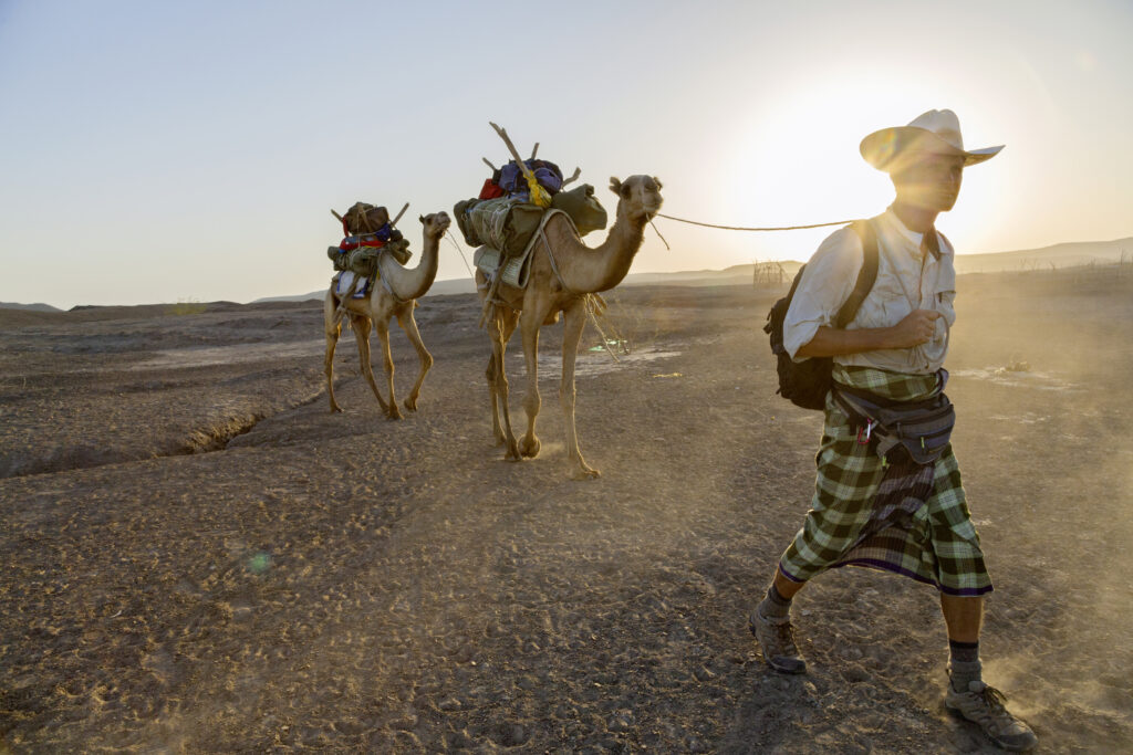 National Geographic Explorer Paul Salopek leads a pair of camels across Ethiopia’s Afar desert. Photograph by John Stanmeyer, National Geographic.