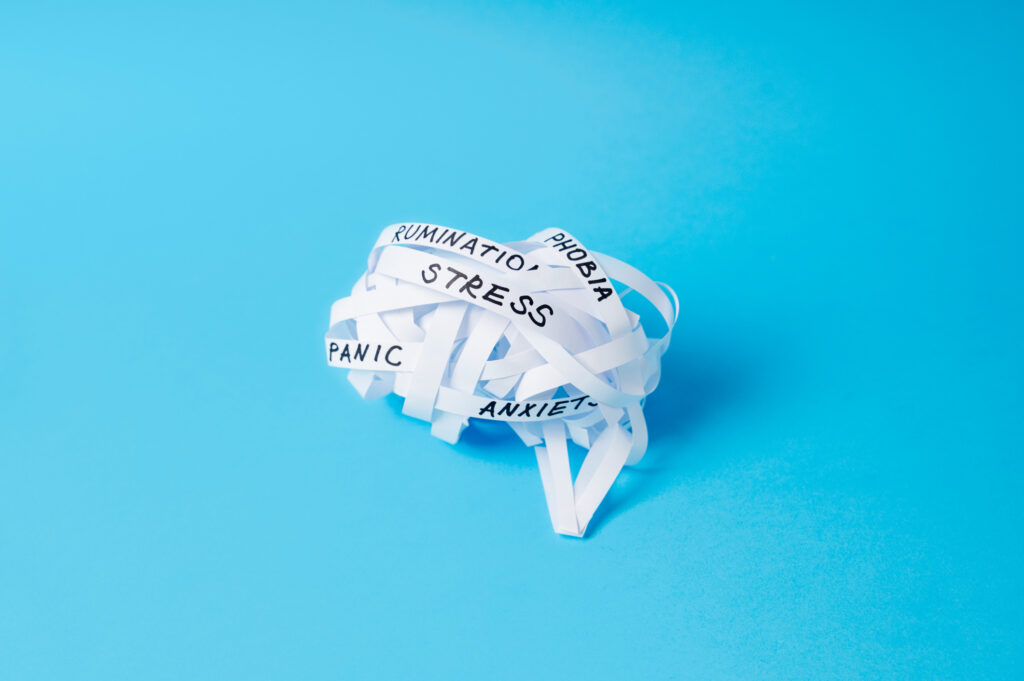 Strips of paper twisted into ball in shape of brain with words STRESS, ANXIETY, PANIC