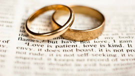 Wedding rings sitting on the 1 Corinthians 13 Bible passage on what love is.
