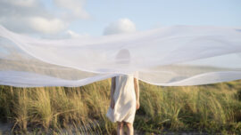 Woman alone behind white veil