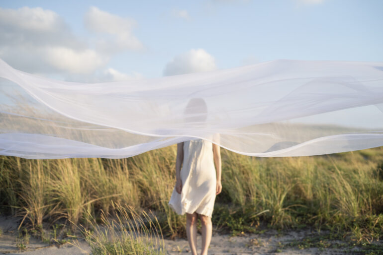 Woman alone behind white veil