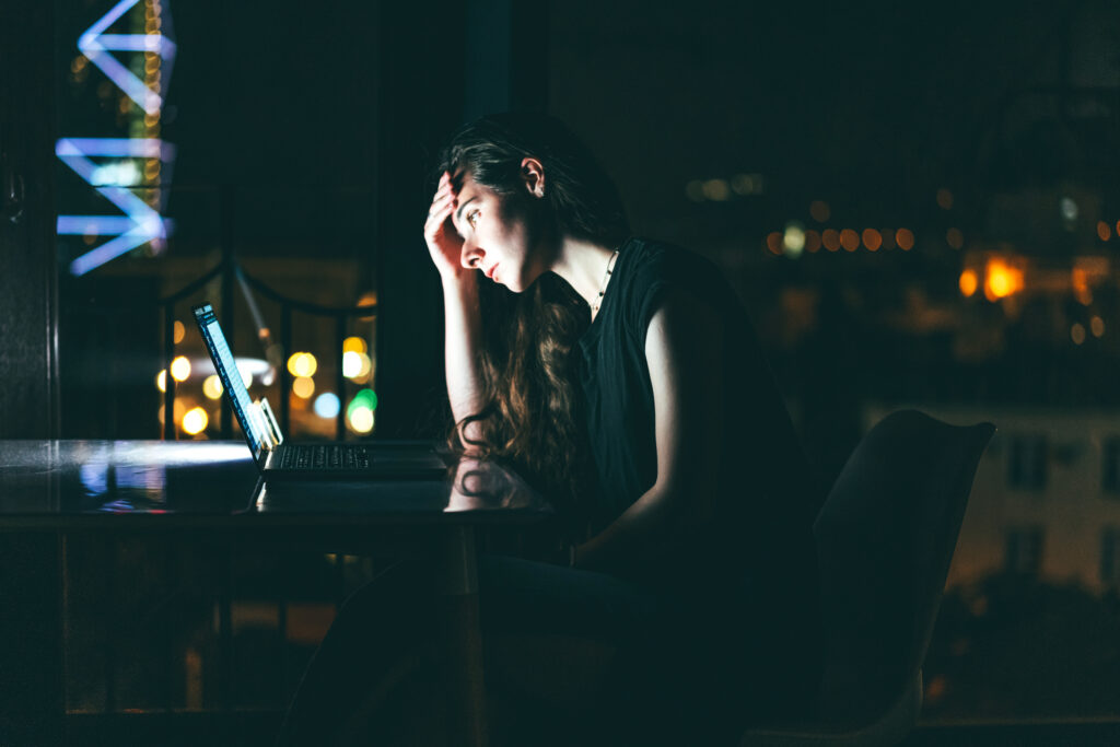 An overworked woman, tired, using laptop at night